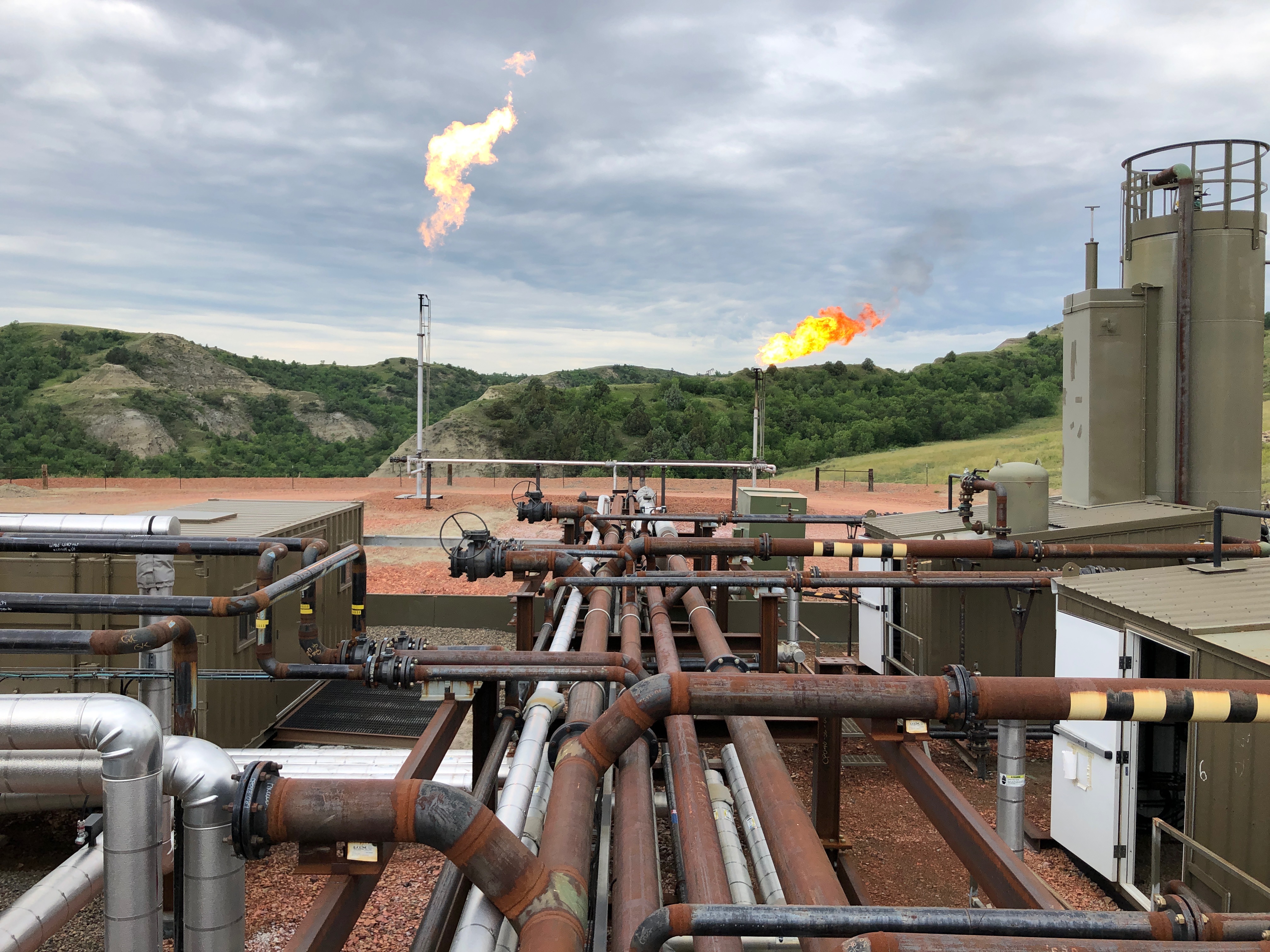 Flaring activity over an active energy facility in a rugged landscape.