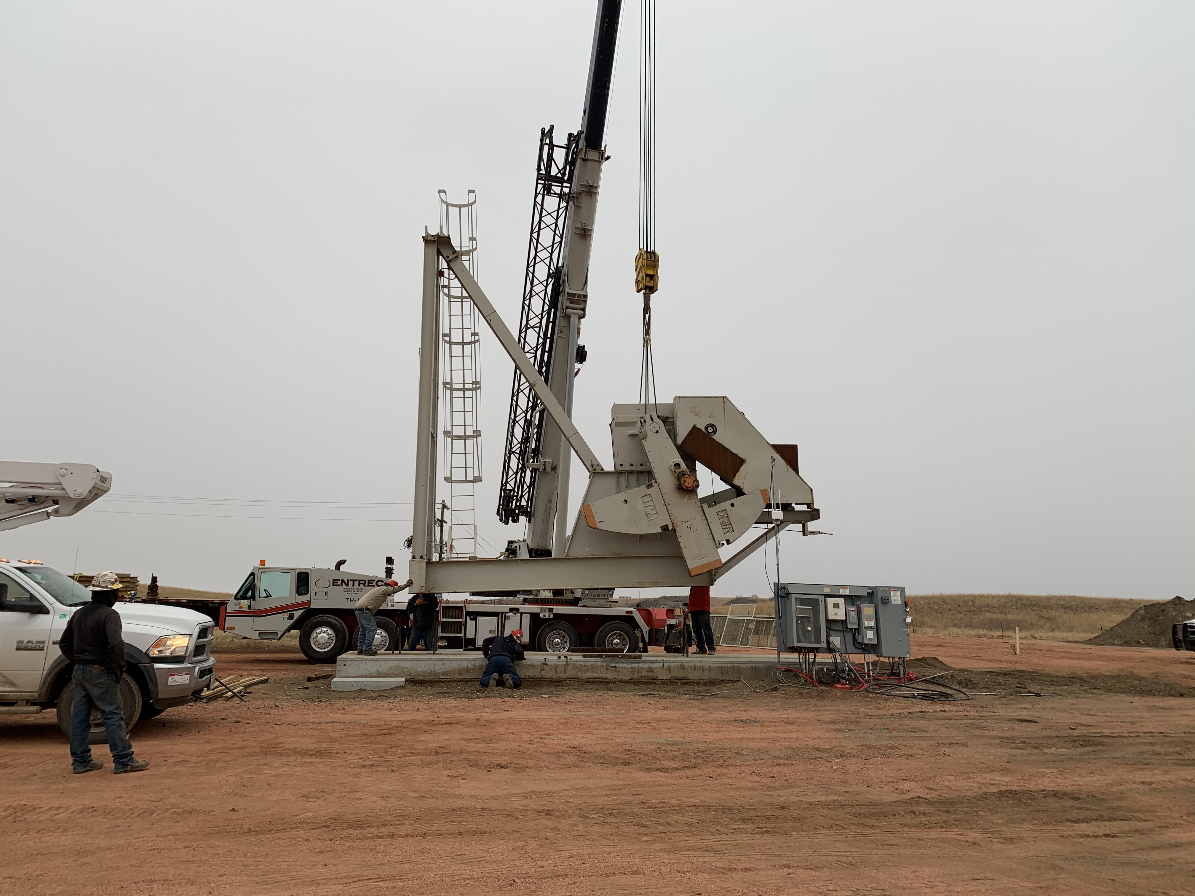 Crane and field crew installing equipment on an active worksite.